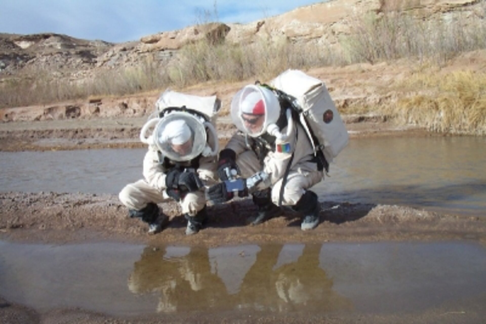 Andrea Fori and Vladimir Pletser collecting a mud sample at the river