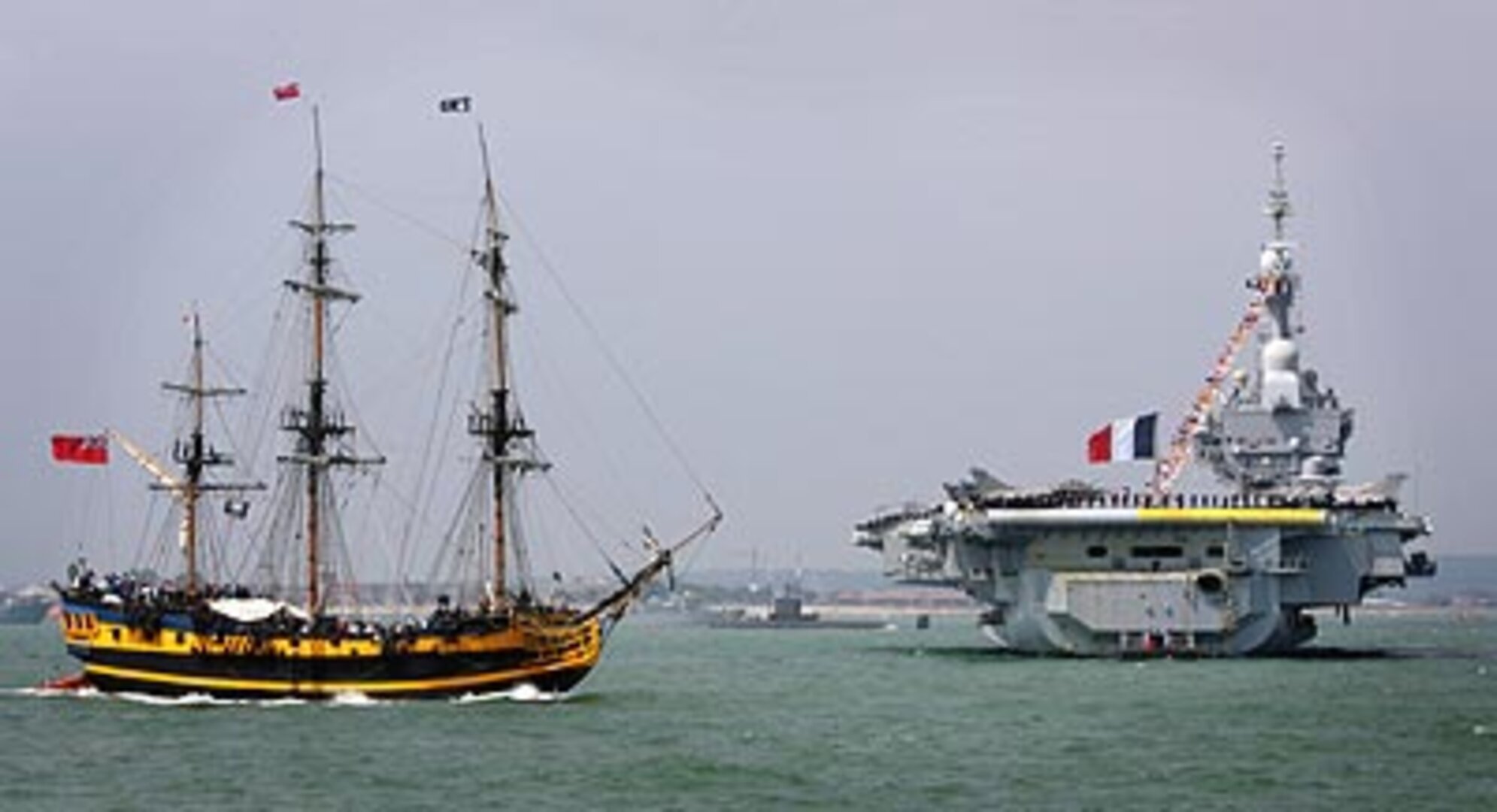 The Grand Turk sails by the French aircraft carrier Charles de Gaulle