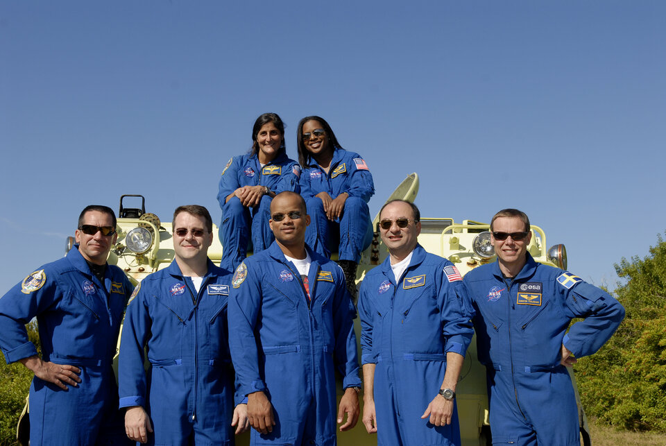 STS-116 mission crewmembers pose next an emergency evacuation vehicle
