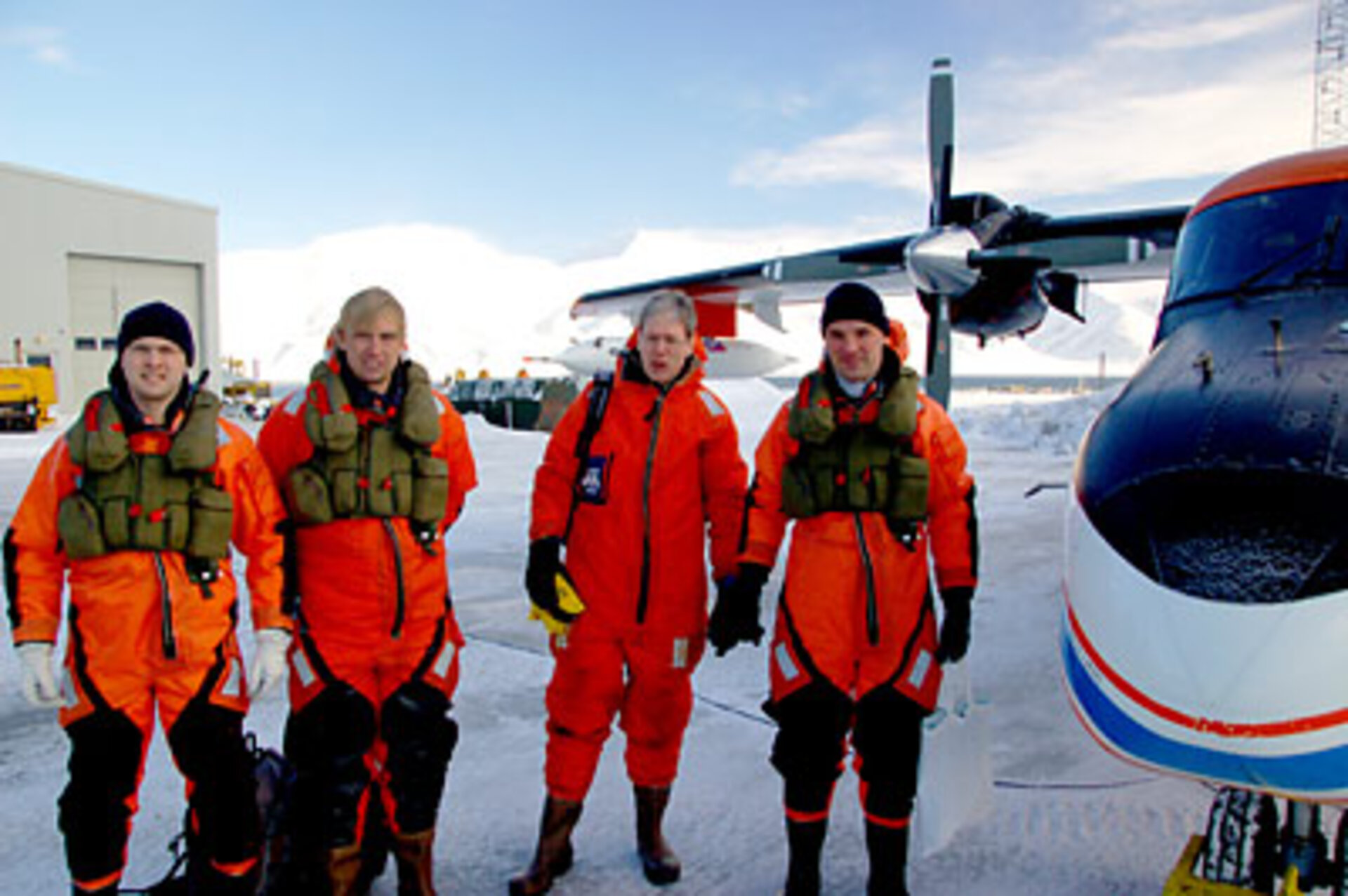 Scientists in sea-survival clothing next to the Polar 2 aircraft from AWI