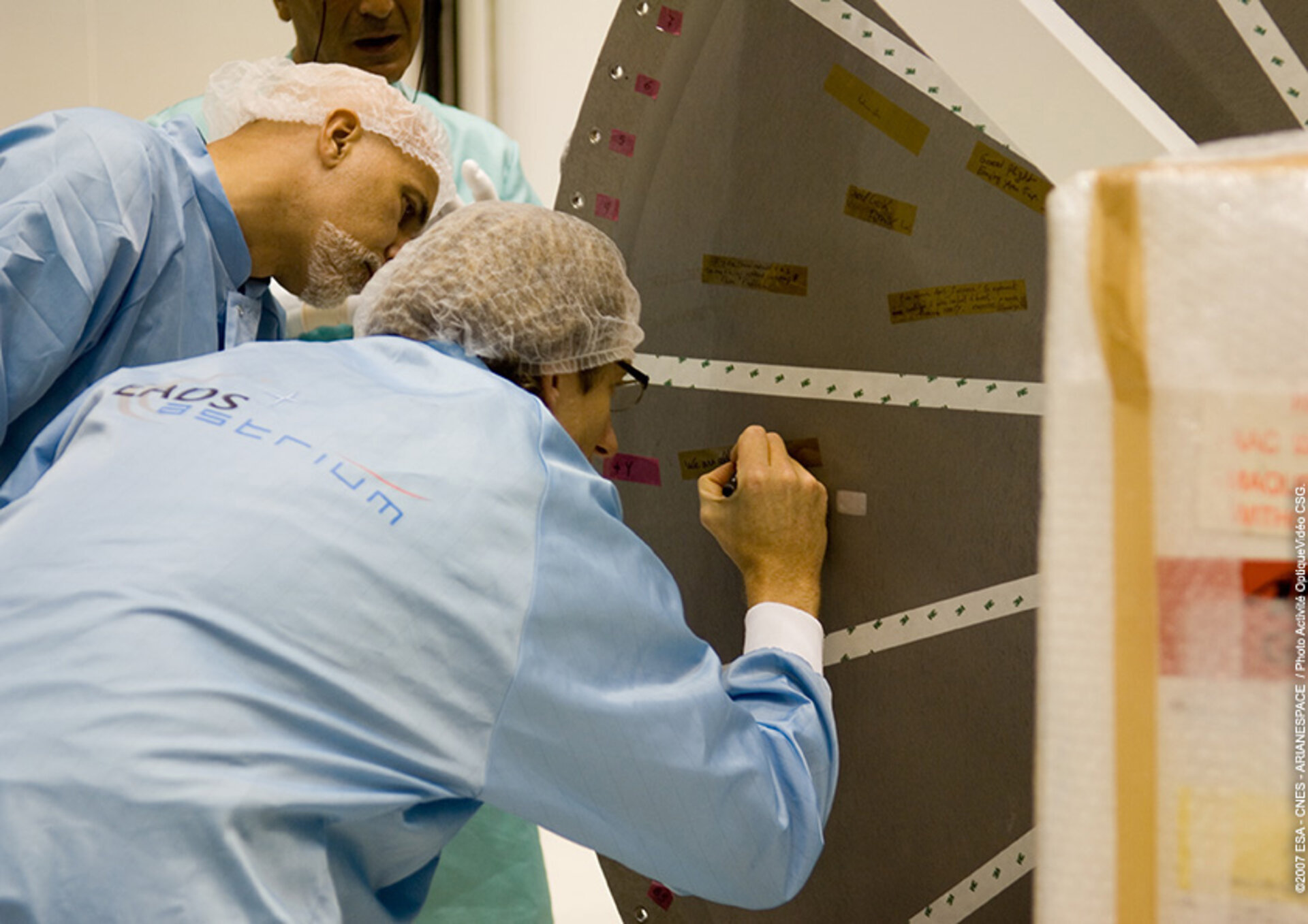 Project team members write messages on the Integrated Cargo Carrier cover