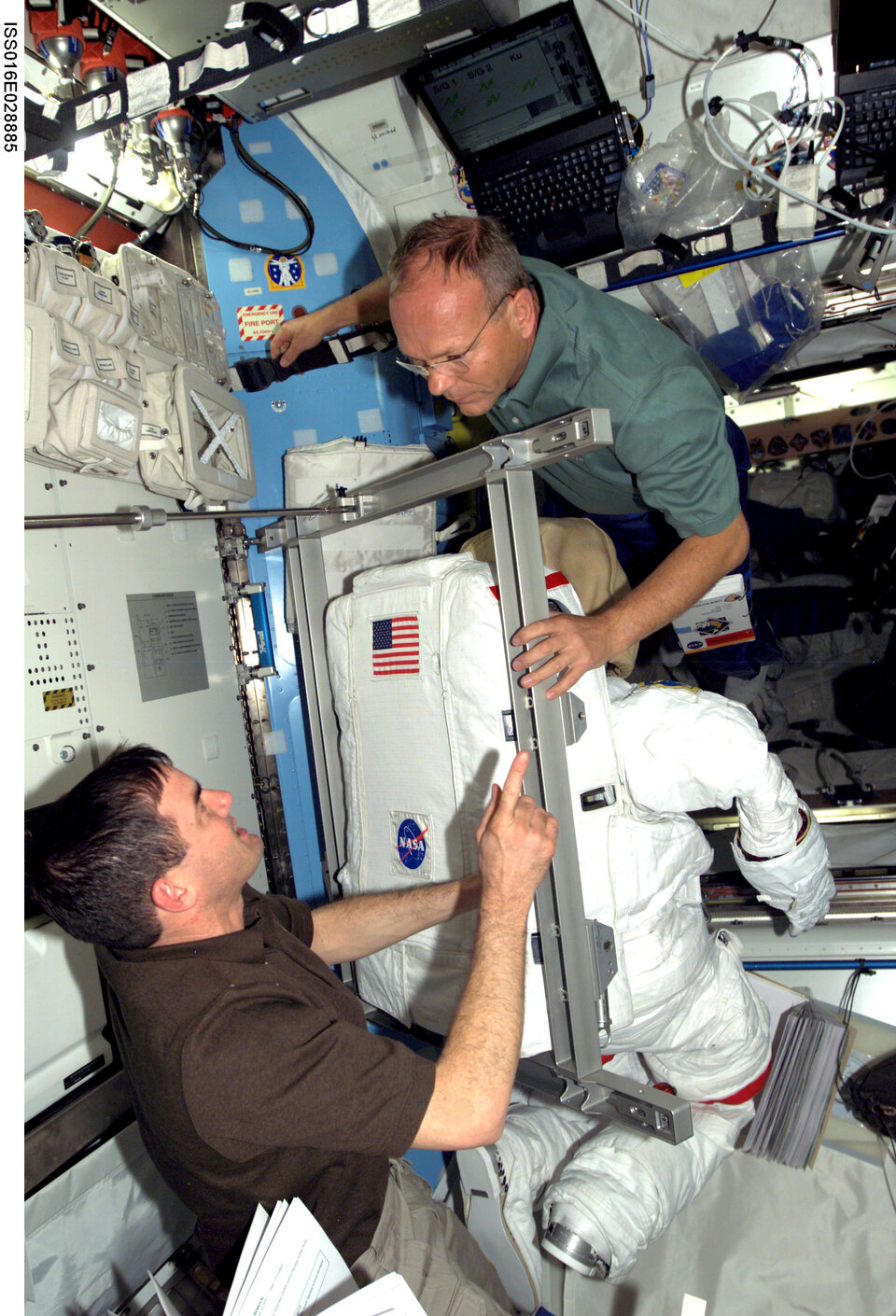 ESA astronaut Hans Schlegel and NASA astronaut Rex Walheim prepare an EVA spacesuit