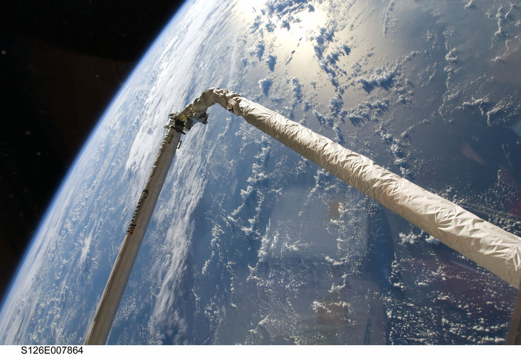 Space Shuttle robotic arm against backdrop of Earth's horizon