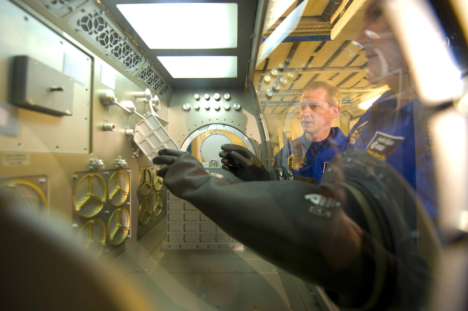 Wat we in de ruimte doen hebben we op de aarde voorbereid: samen met de Nederlandse ESA-astronaut André Kuipers werk ik hier met een model van de <i>Microgravity Science Glovebox</i> in  het <i>European Astronaut Centre (EAC)</i> in Keulen