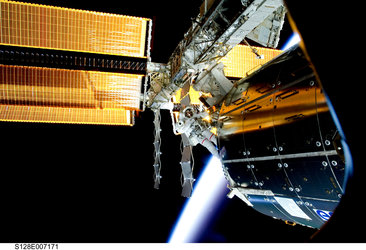 NASA astronaut John Olivas works to remove experiment pallets from the external platform on Columbus