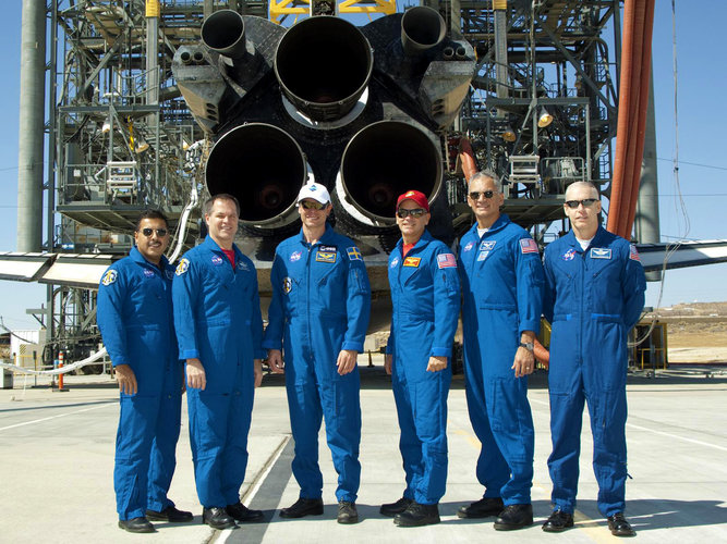 STS-128 crew line up behind Discovery