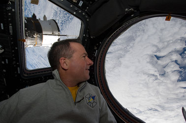 Stephen Robinson looks through a window in the Cupola