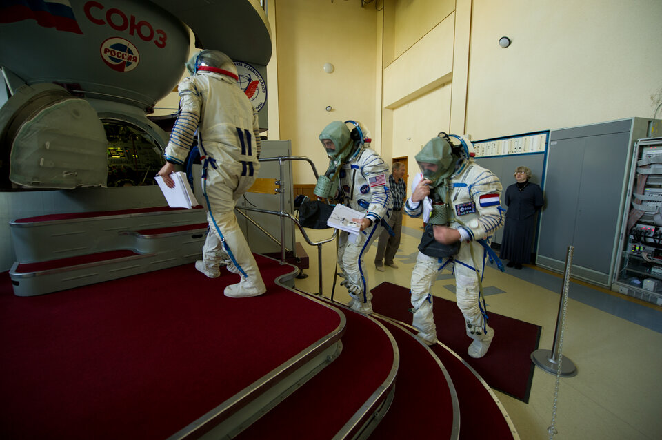 Training for emergencies in one of the Soyuz TMA simulators. In the event of fire or air contamination, the crew dons gas masks and carry on working.