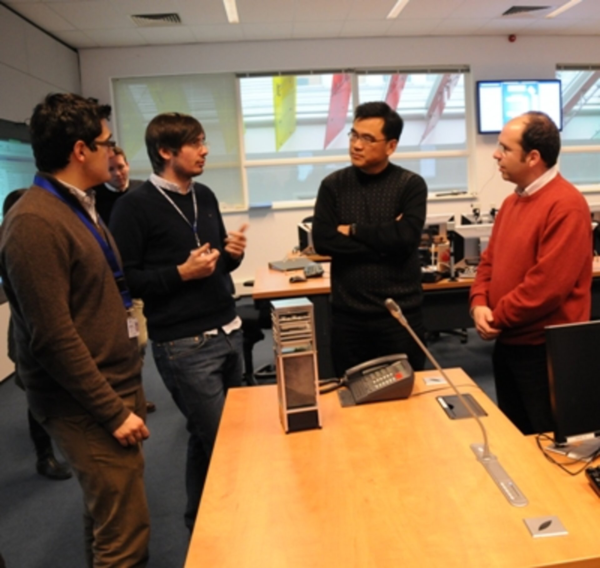 OPS-SAT team members around the 1:1 scale model of the CubeSat