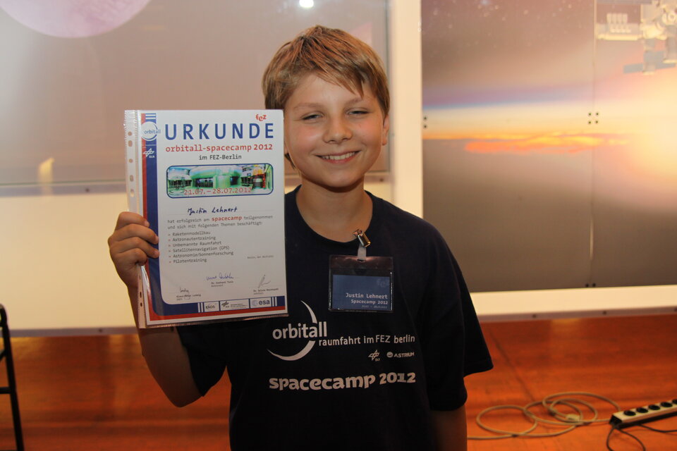 Stolz präsentiert ein kleiner Raumfahrer sein Astronauten-Diplom