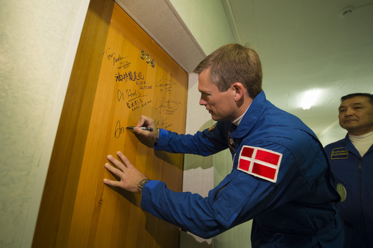 Andreas Mogensen performs the traditional door signing at the Cosmonaut Hotel 