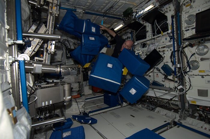 Astronaut André Kuipers mit textilen Transporttaschen in der ISS