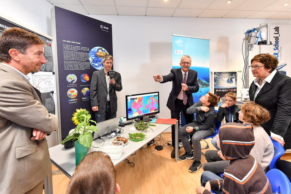 Prof. Michael Rast erklärt Bundeswirtschaftsministerin Brigitte Zypries und Kindern eine Thermalkamera zur Erdbeobachtung 