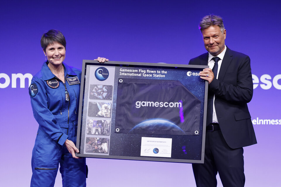 Samantha Cristoforetti, astronauta dell'ESA, e il Vicecancelliere tedesco Robert Habeck con la bandiera di Gamescom che ha sventolato nello spazio sulla Stazione Spaziale Internazionale.