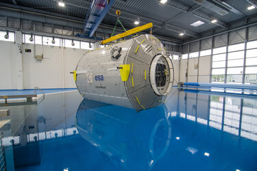 A mock-up of the European Columbus laboratory is submerged into the Neutral Buoyancy Facility (NBF) at the European Astronaut Centre (EAC).