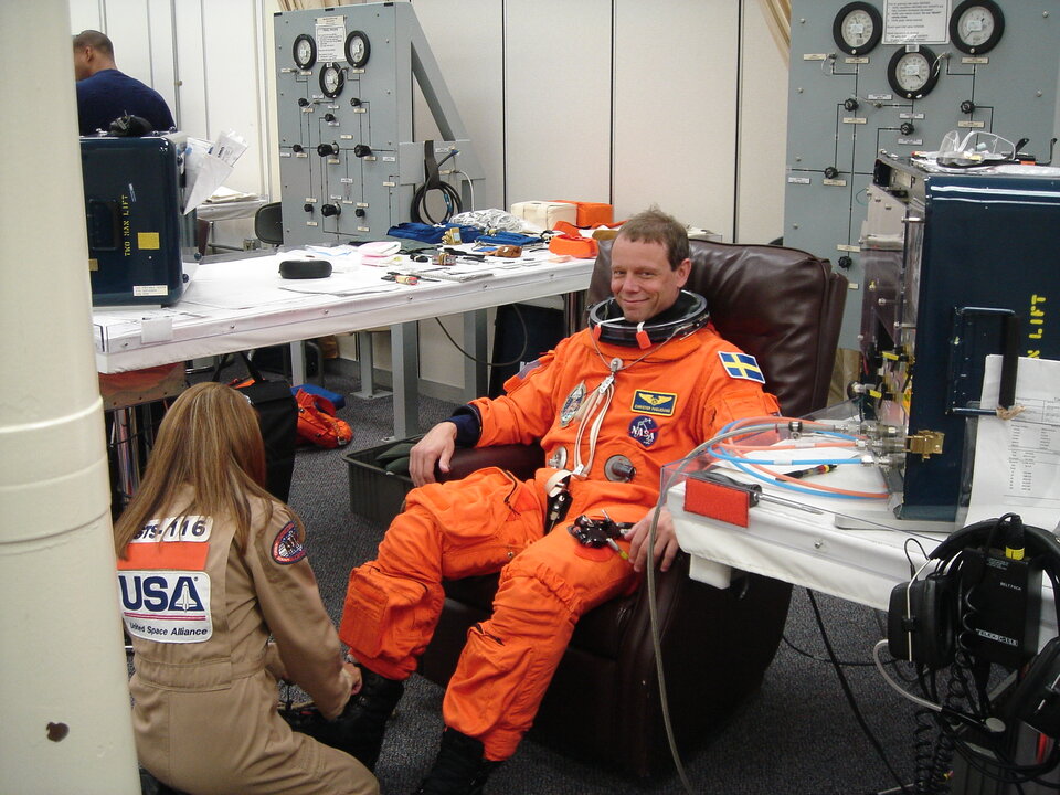 Christer Fuglesang is helped into his orange Advanced Crew Escape Suit (ACES) in preparation for the practice countdown