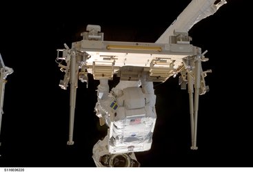 Fuglesang stands on a platform at the end of the Station's robotic arm