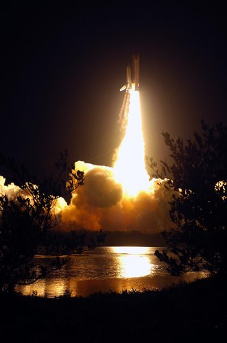 Space Shuttle Discovery soars away from the fiery clouds on Launch Pad 39B on mission STS-116