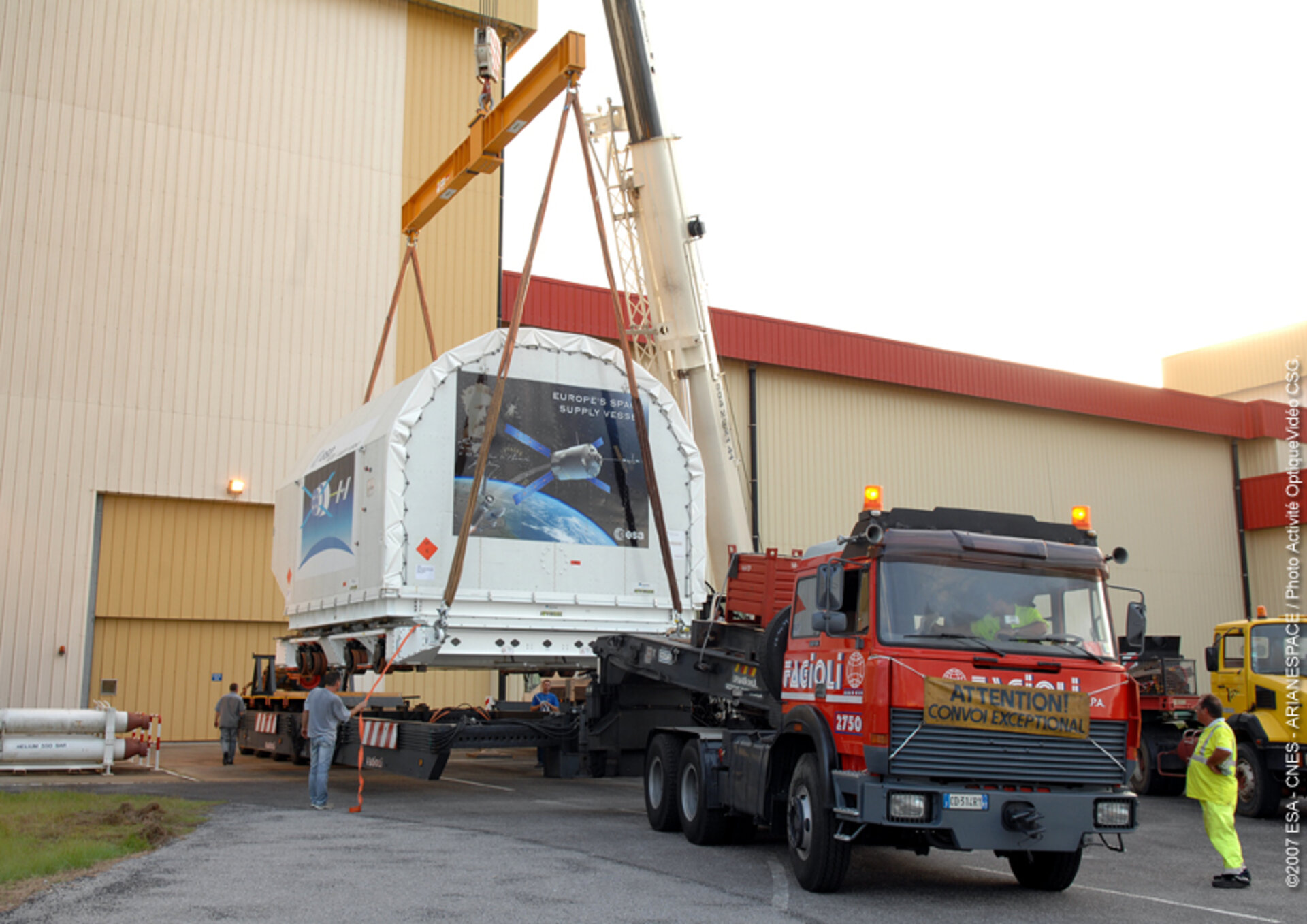 Container holding the ATV Integrated Cargo Carrier is lifted off the back of a truck at Europe's Spaceport in Kourou
