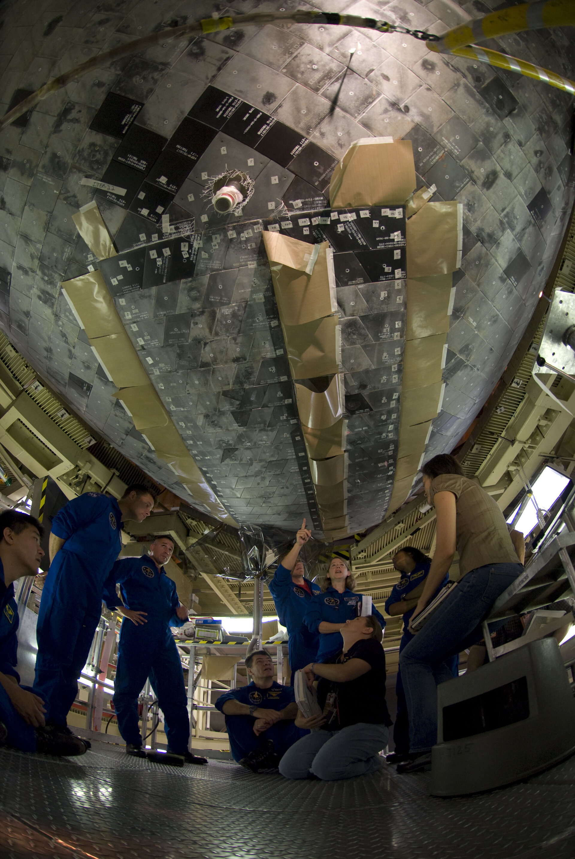 Crew of STS-120 with Paolo Nespoli inspect Discovery's heatshield during the CEIT at KSC