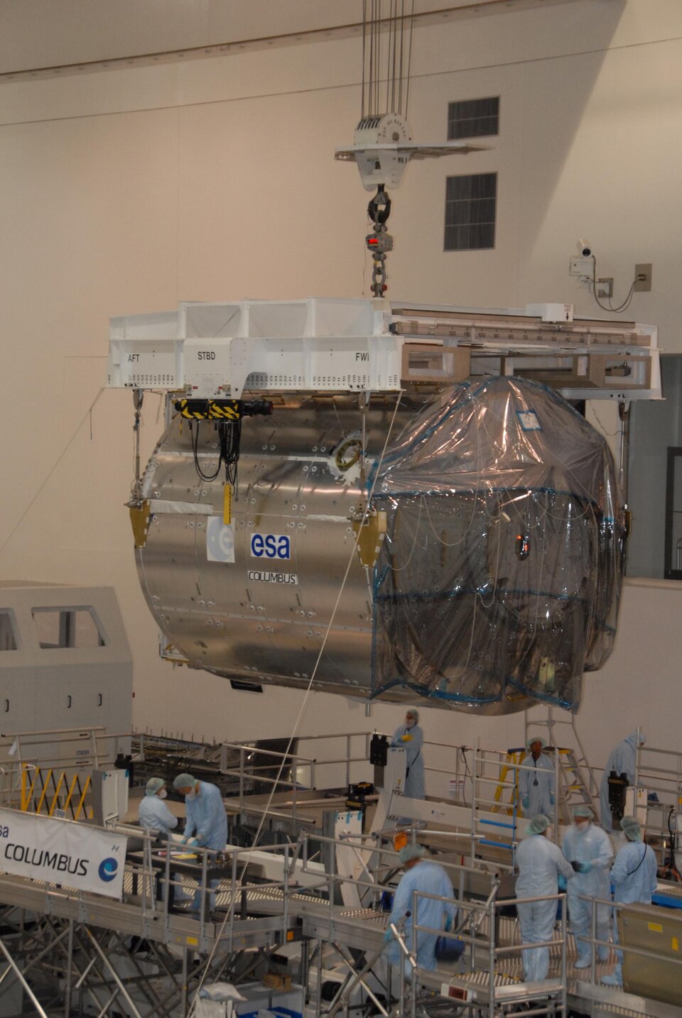 An overhead crane lifts the European Columbus laboratory from its stand