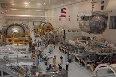 An overhead crane lifts the European Columbus laboratory module away from its stand