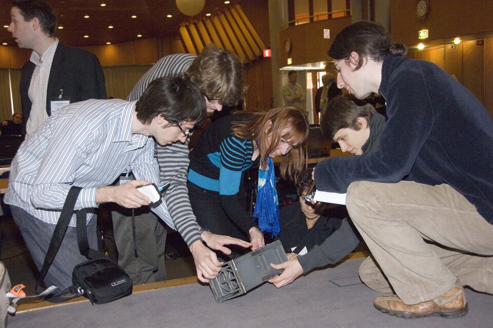 Workshop participants inspect a CubeSat deployer