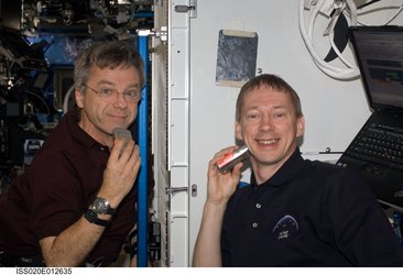 Frank De Winne and Robert Thirsk shave with electric razors in Destiny laboratory