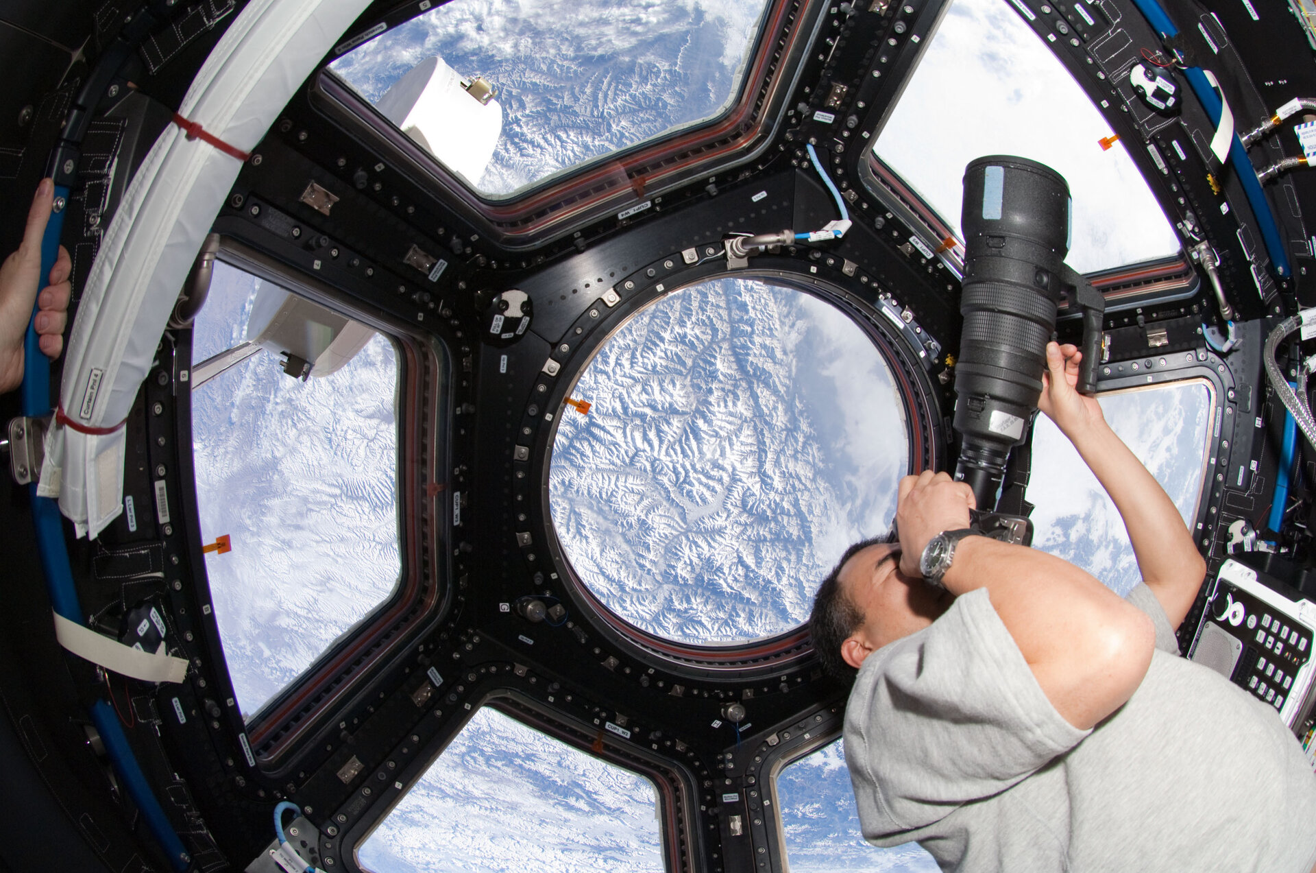 Soichi Noguchi uses a still camera at a window in the Cupola