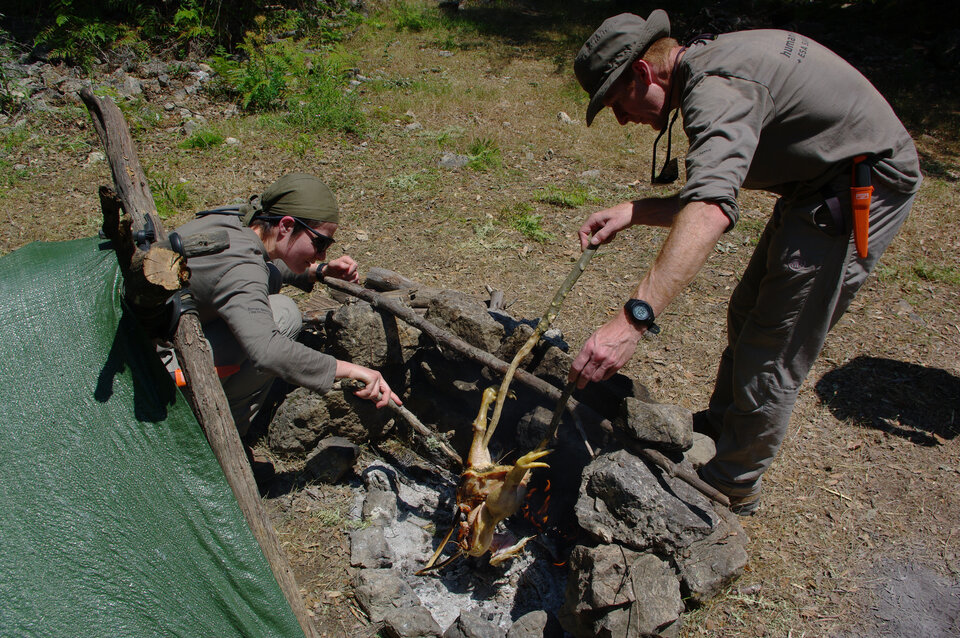 Tim Peake (vpravo) připravuje oběd na ohni.