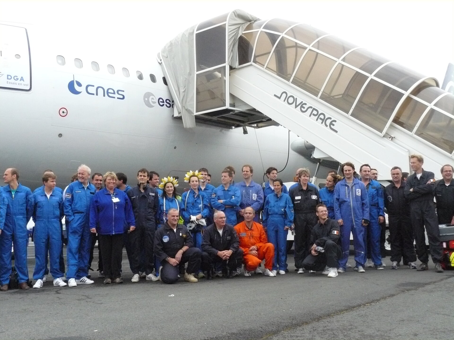 Participants pose under the plane after the flight