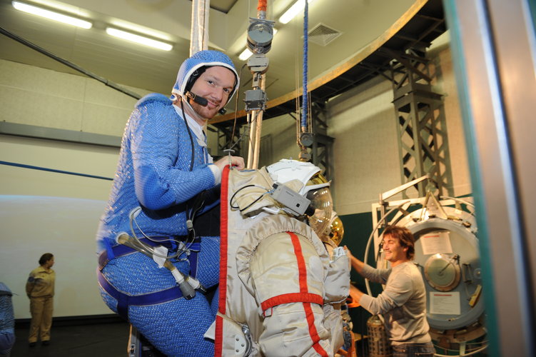 Alexander climbing into his spacesuit