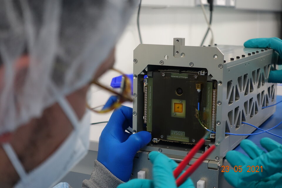 A LEDSAT team member carefully inserts into the test pod ready for the vibration test