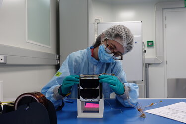 Student inspecting ISTSat-1 model before vibration test