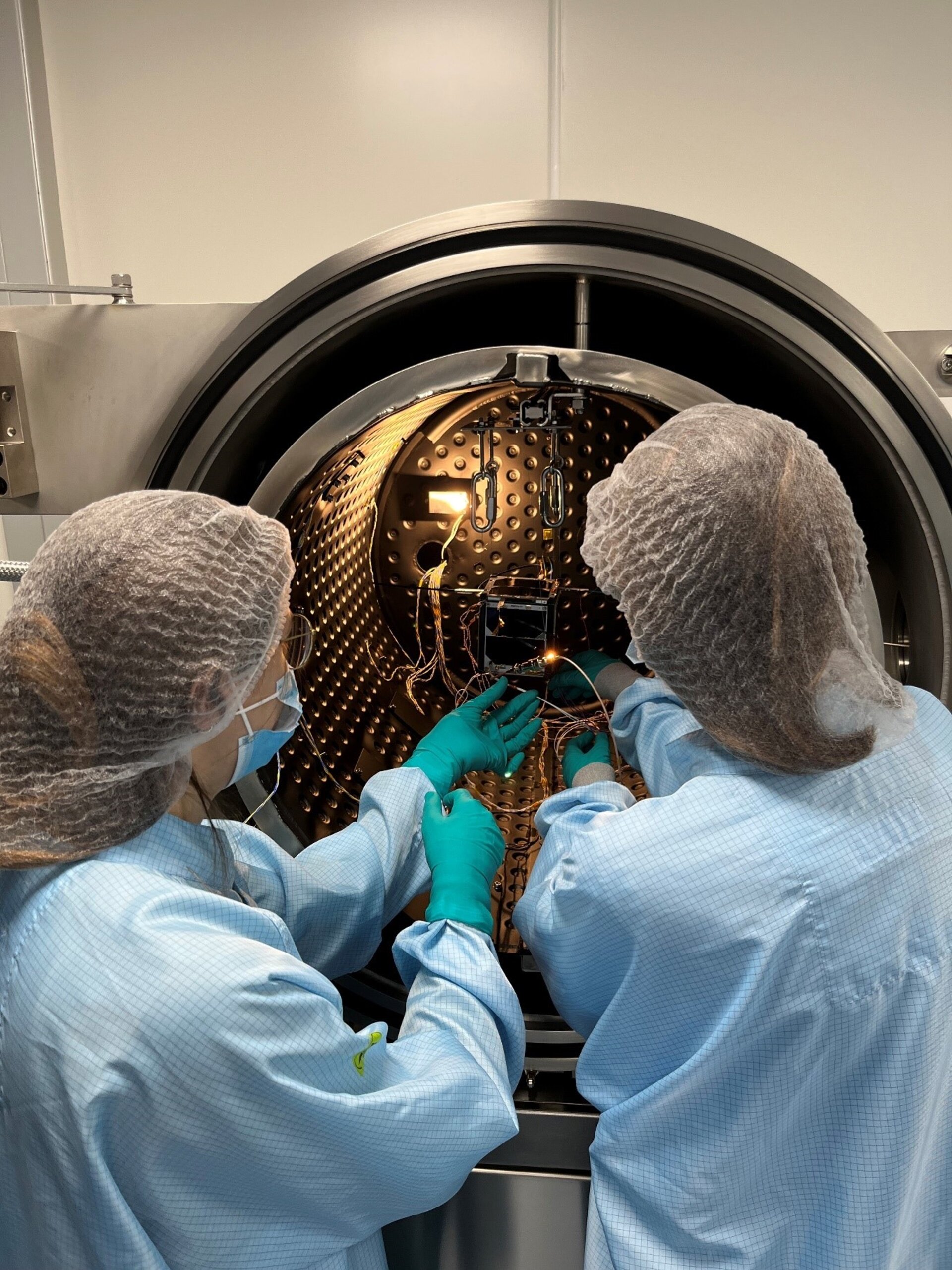 Students inspecting ISTSat-1 in thermal vacuum chamber